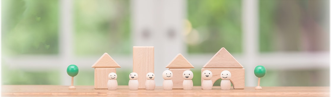 シンプルな人形の７人家族が、気の家の前に並んでいる写真