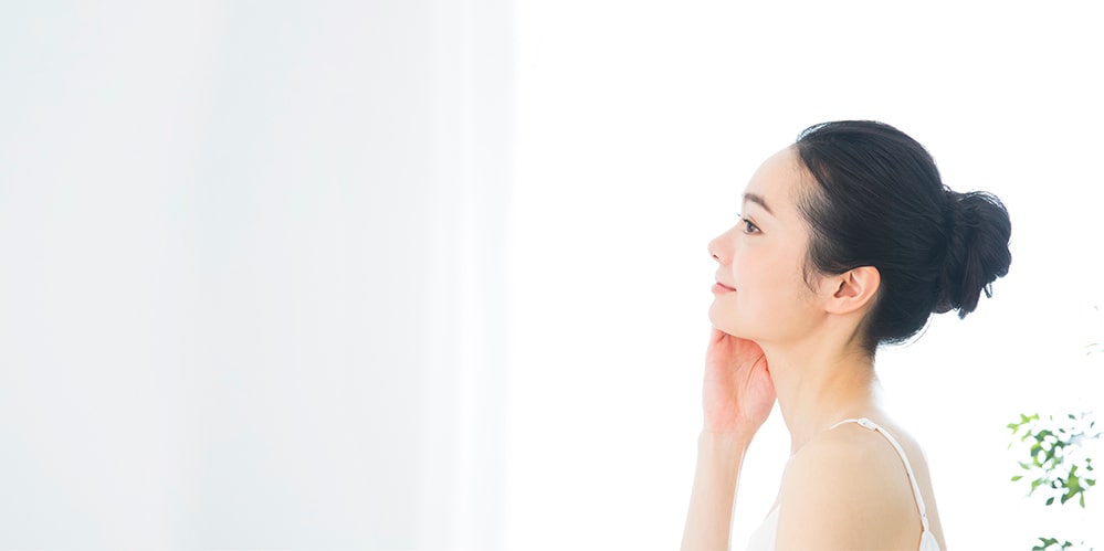 木々を背景に女性が笑顔でストレッチをしている写真。